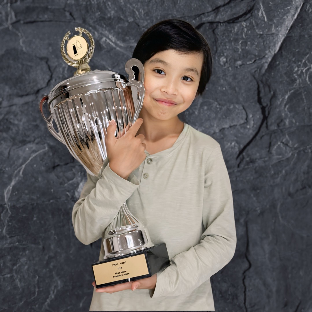 Lucas Yao holding a chess trophy in front of a stone wall